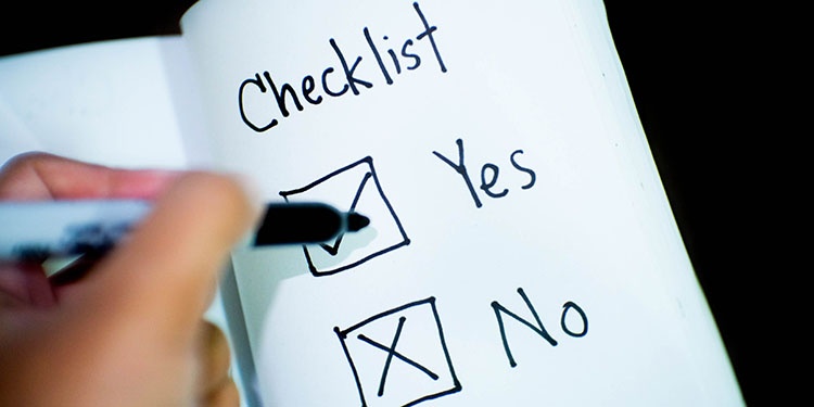 A hand with a pen checking Yes on a Yes/No checklist