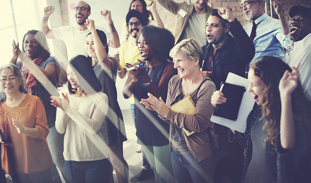 Group of people standing, smiling and clapping