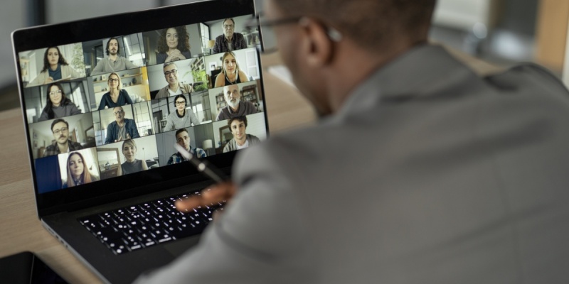 man looking at computer with faces of other people